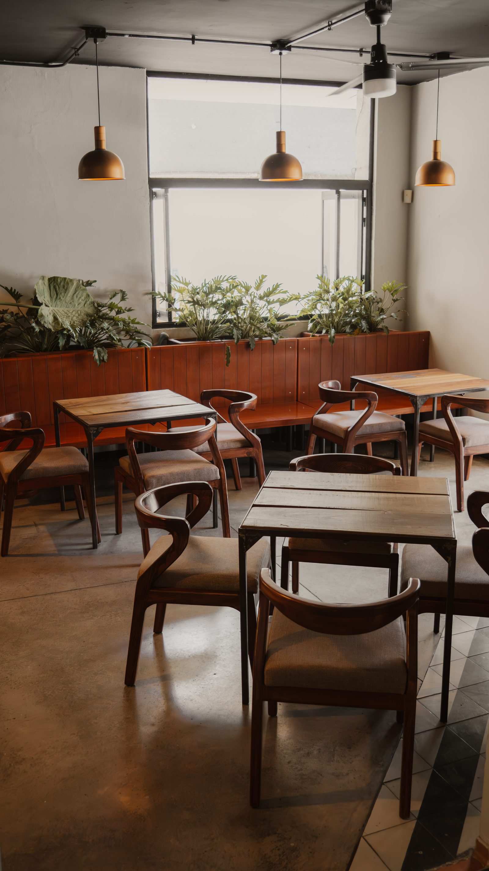 Interior de Kieto: mesas de madera, plantas y luz natural